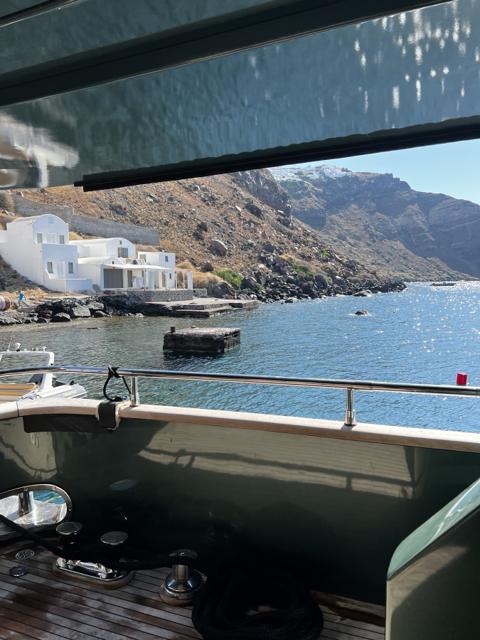 The Santorini caldera seen from the water: white houses at the foot of the cliff, past a boat's rail