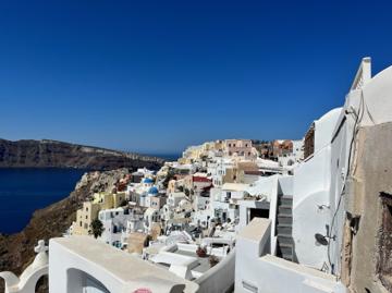 White houses and blue domes stepping down the caldera rim above the sea, Santorini