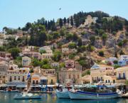 Pastel neoclassical houses and boats around the harbour on Symi