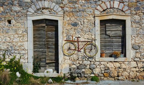 A bicycle mounted on the stone façade of a traditional Mani building