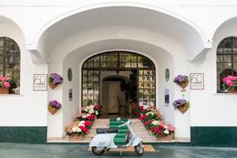 The hotel entrance under white arches, a Vespa parked beside the flowers
