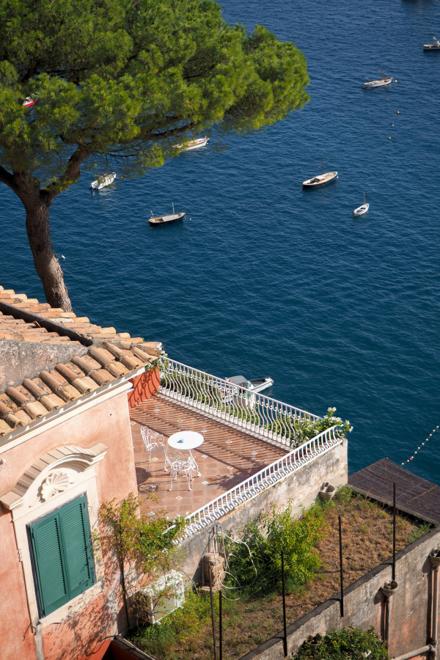 A tiled villa terrace above the water on the Amalfi Coast, boats moored below