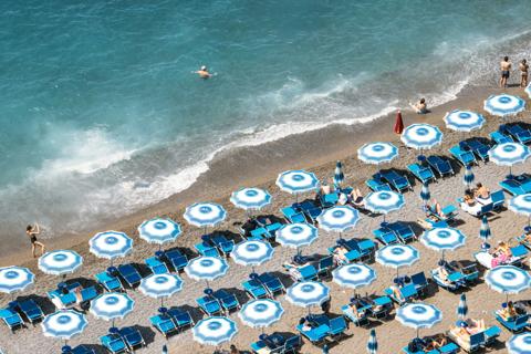Striped umbrellas and loungers on an Amalfi Coast beach, seen from above
