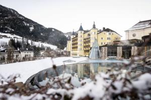 ADLER Spa Resort Dolomiti — Tyrolean facade behind the outdoor thermal pool, winter