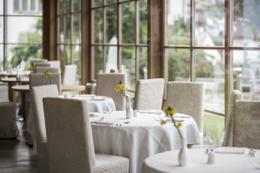 ADLER Spa Resort Dolomiti — dining room with white linens, daffodils, panoramic windows