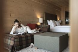 ADLER Lodge Alpe — pine-clad chalet suite with plaid reading bench