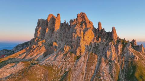 Limestone spires going pink at sunset, a hut on the ridge below them