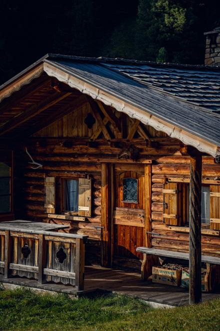 A carved wooden hut with a shingle roof and a bench by the door
