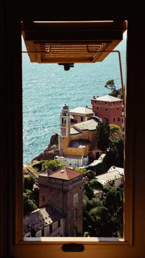 Portofino through an open window: the church campanile, terracotta roofs and the Ligurian Sea beyond