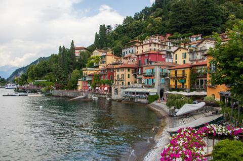 A lakeside village stacked up the hillside, boats pulled onto the shore