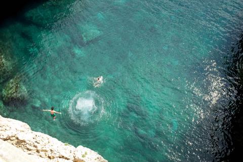 Swimmers in a green cliff cove at Polignano a Mare, Puglia