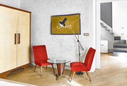 G-Rough — open-plan suite with red mid-century chairs, Fine flag artwork, glass coffee table