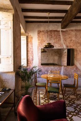 G-Rough — suite with distressed pink plaster walls, brass pendant, encaustic tile floor