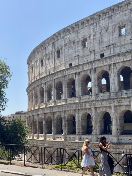 The Colosseum seen from the road above, with people walking past the railing