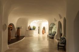 Romazzino — reception with sculptural white plaster vaults, terracotta urns, hexagonal stone floor
