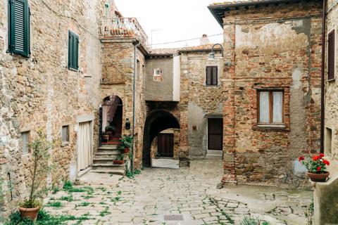 A cobbled lane between old stone houses, geraniums by the doors
