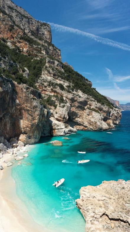 Limestone cliffs dropping into a cove with boats on the water