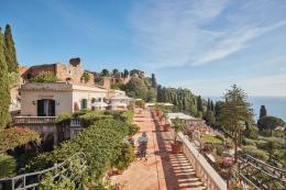 Belmond Grand Hotel Timeo — terracotta garden terrace with painted topiary urns, Greek Theatre ruins on the hillside above