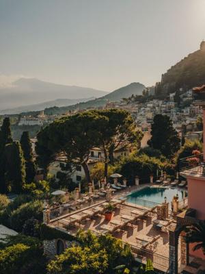 Belmond Grand Hotel Timeo — pool deck at golden hour, Taormina rooftops stretching to Etna on the horizon