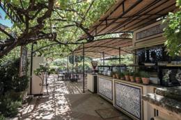 Belmond Grand Hotel Timeo — restaurant under a grape pergola with painted tile bar and sun-dappled terracotta floor