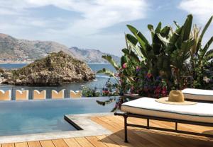 Villa Sant'Andrea — infinity pool framed by banana palms, view across the Bay of Mazzarò to Isola Bella