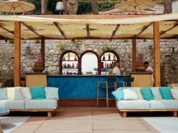 Villa Sant'Andrea — beach bar with blue-tiled counter, sail awning, striped cushions