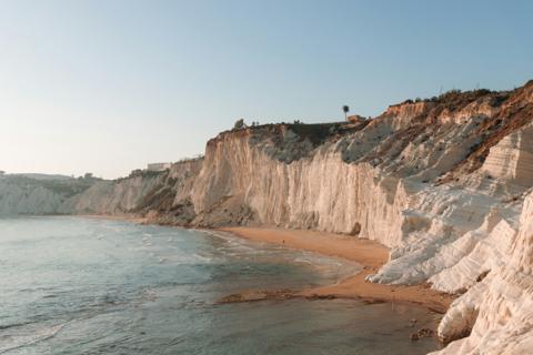 Layered white cliffs dropping to a sand beach on the Sicilian coast at sunset