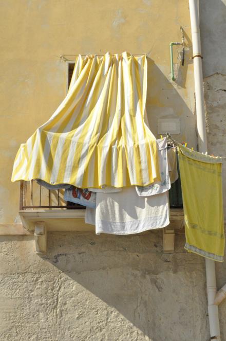 A striped awning and washing hung out over a balcony on an ochre wall