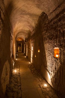Eremito — candlelit stone corridor, candles in wall niches