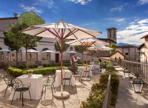 Palazzo Seneca, Norcia — backyard garden with parasols and the historic centre tower