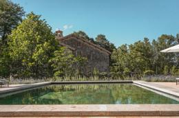 Vocabolo Moscatelli — outdoor pool with the stone monastery facade behind, lavender beds