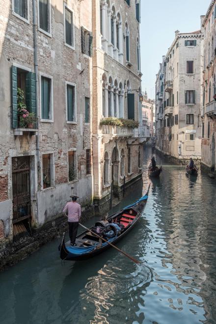 A gondola on a narrow Venetian side canal, buildings rising straight out of the water