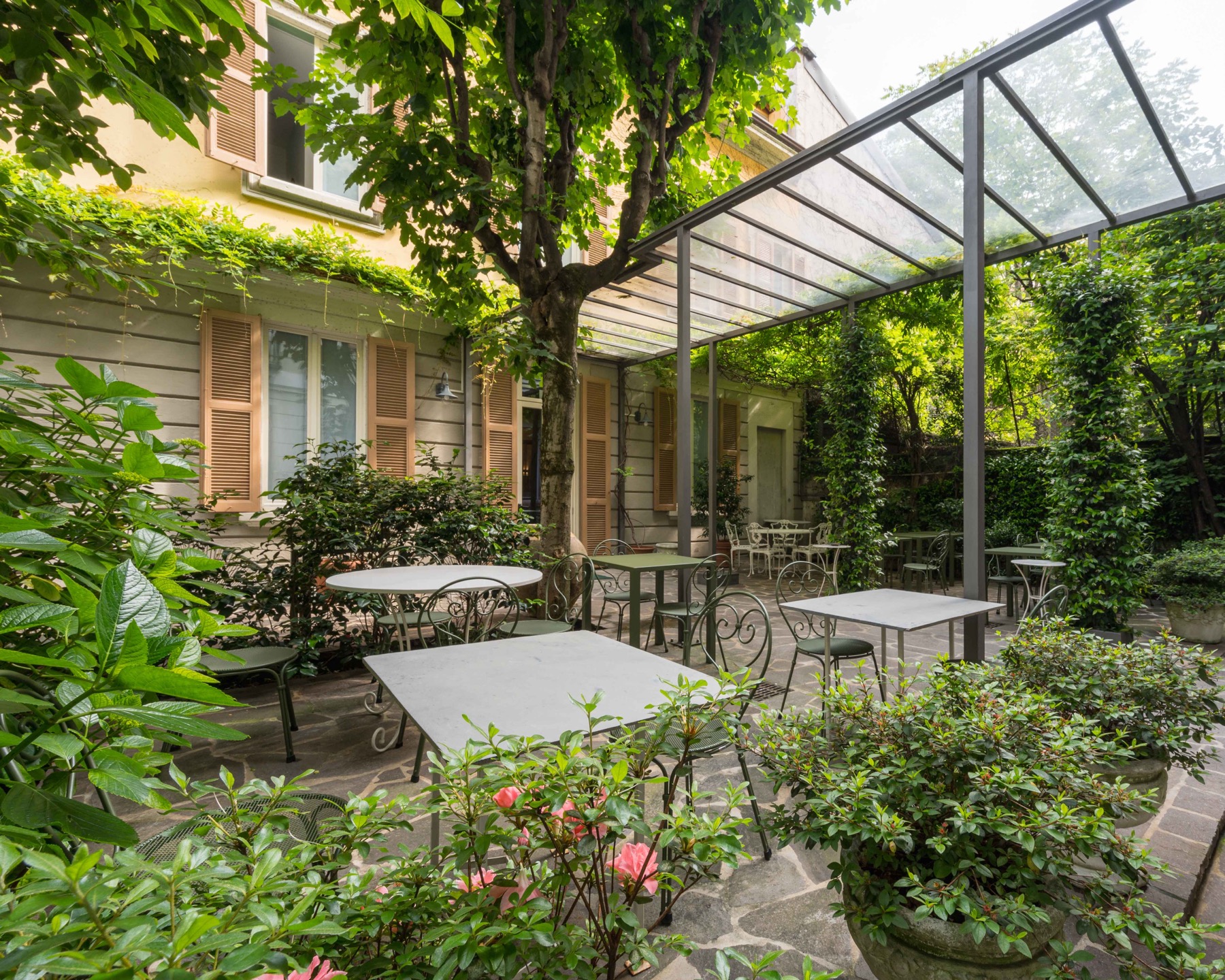 Antica Locanda Leonardo — inner garden courtyard with iron tables under a vine-covered pergola