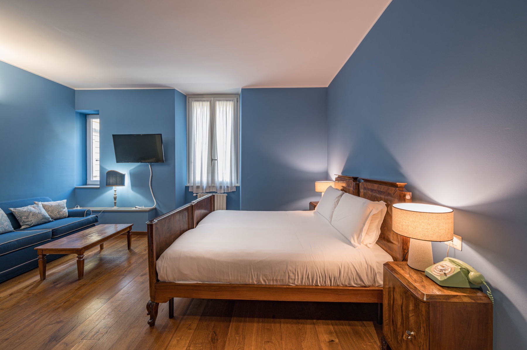 Antica Locanda Leonardo — blue-walled Junior Suite with antique wooden bed and vintage telephone
