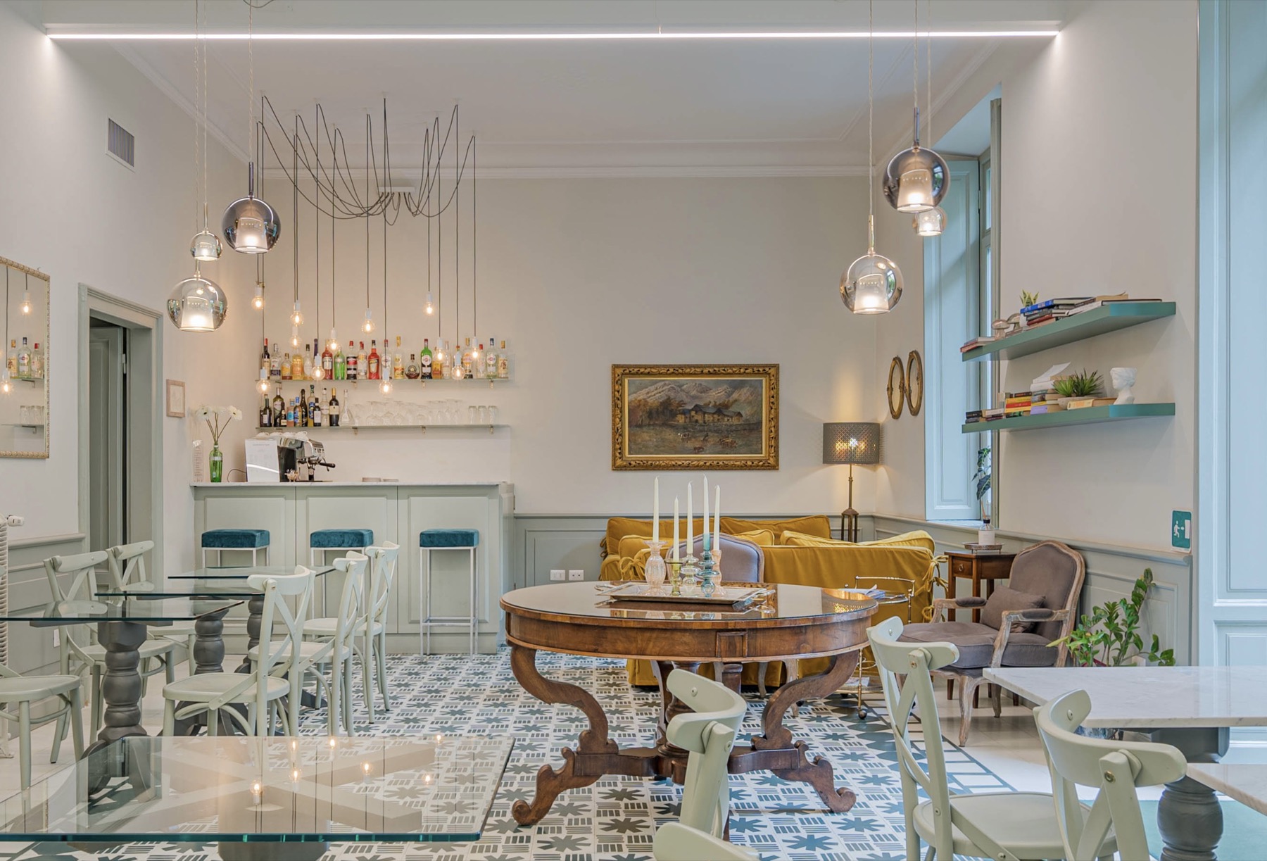 Antica Locanda Leonardo — bright breakfast room with chandelier, mosaic floor, mid-century tables