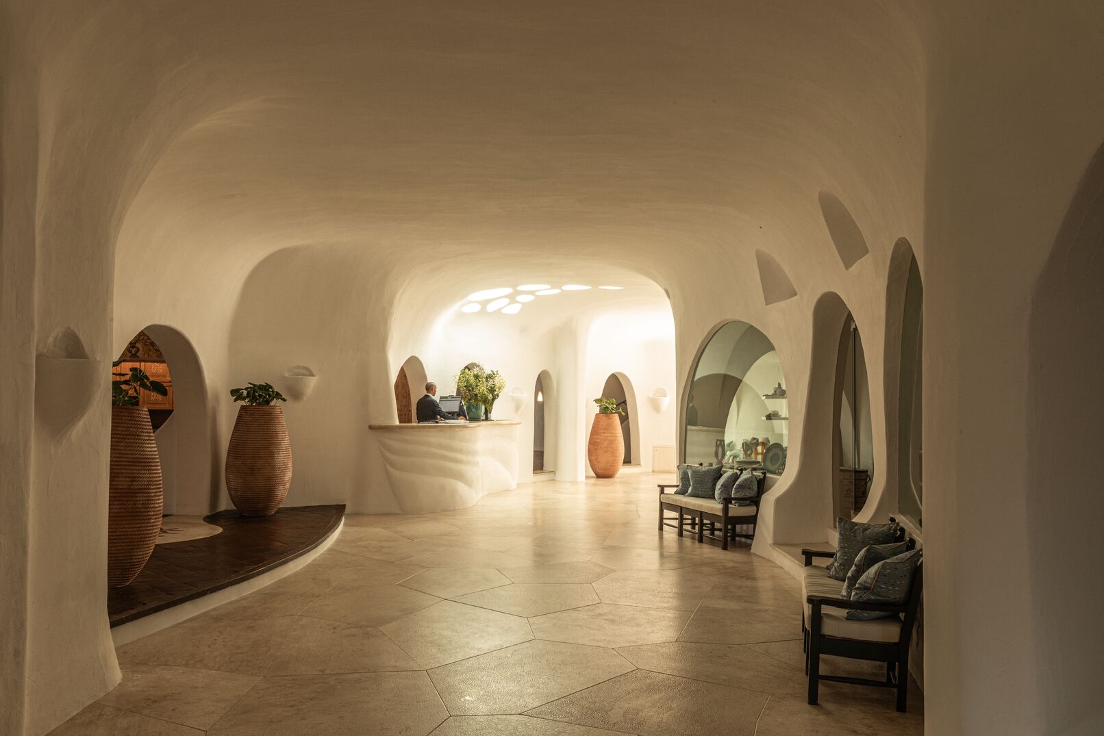 Romazzino — reception with sculptural white plaster vaults, terracotta urns, hexagonal stone floor