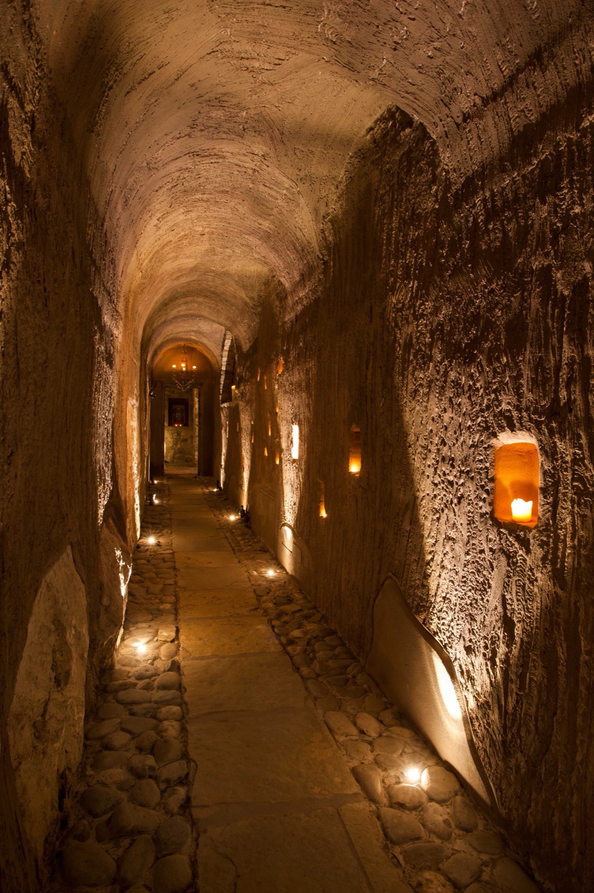 Eremito — candlelit stone corridor, candles in wall niches